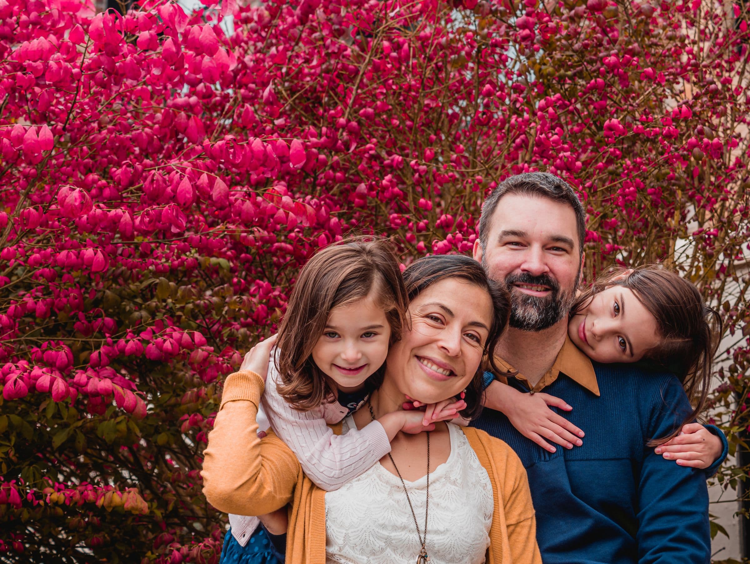 Smiling family of four hugging outdoors